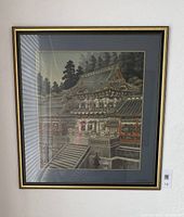Frontal view of framed unsigned antique pagoda tapestry art showing temple structure with surrounding trees, double matting, and black and gold frame.