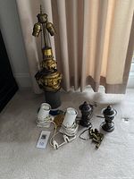 Lighting lot with converted oil lamp, shrine lights, mini spotlights, and lamp finials displayed on carpeted floor near curtain backdrop