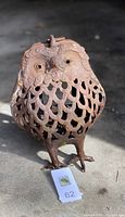 Photo of a rusted metal outdoor garden owl ornament standing upright showing front detail with lattice feather cut-out design and facial features.