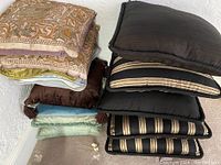 Pile of decorative throw pillows showing various colors, fabrics, and textures including embroidered, velvet, and striped