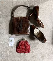 Photo showing a pair of brown alligator leather women's shoes size 8, matching alligator leather handbag, and a small red antique beaded purse on a grey carpet.
