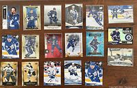Full overhead photo showing all 18 Toronto Maple Leafs hockey cards arranged in rows on wooden surface