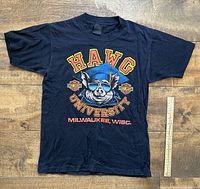 Photo of the full black T-shirt with Hawg University graphic laid flat with ruler for size reference.