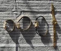 Four vintage wristwatches laid out on a cloth surface showing Bulova, Birks, Facet, and Timex watches with metal and leather bands.