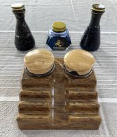 Full view of the vintage bakelite double inkwell with two ink wells and their covers, front and center. Three ink bottles set behind it: two black glass Lano-Wax Esquire and one hexagonal blue Watermans ink bottle with yellow cap.