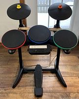 Complete Band Hero drum set showing all drum pads, cymbals, foot pedal, and two drumsticks at the back.