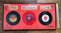Full view of framed triple 45 rpm record piece with red background, 'Old School Love' text and rhinestone decorations.
