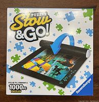 Front of box showing product name, mat image with puzzle pieces, and capacity for up to 1000 piece puzzles