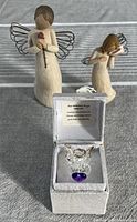 Three angels displayed together: two larger ceramic angels with metal wire wings and a small glass angel in a display box.