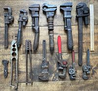 Overview photo showing all thirteen vintage tools arranged on wooden surface along with a ruler for scale.
