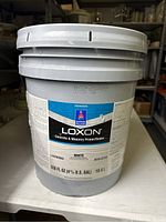 Front view of sealed 5 gallon bucket of Sherwin-Williams Loxon Concrete & Masonry Primer/Sealer paint showing label with product information and volume.