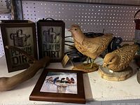 Photo showing two 'Play in the Dirt' lamp boxes, two carved wooden bird figurines, a wooden branch decor piece, and a small framed painting of birds on a wire.