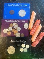 Photo showing three US proof sets from 1981, 1983, 1985 and four penny rolls
