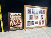 Two framed baseball art pieces placed side by side on a surface against a dark background. One is a rectangular wooden plaque with a sepia photo of three Yankees players. The other is a wooden-framed collage of Phillies cards and images.