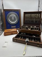 Overall shot of Gorham silverware set in wooden box with framed military plate and wooden box alongside.
