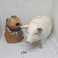 Photo showing brown pig pitcher and white pig cookie jar side by side.