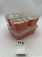 Four pink Pyrex containers stacked with lids visible