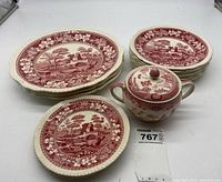 Set of 10 Willow pattern plates in red and white with floral and scenic design, arranged in two stacks with a sugar bowl in foreground.