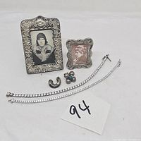 Photo showing entire lot with two CZ tennis bracelets, two silver photo frames, and two single earrings on white background.