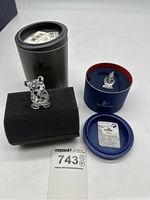 Bear figurine displayed on black foam with gray circular box behind.