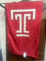 Full front view of large red flag with white T symbol hung vertically.
