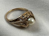 Angled front view showing natural pearl and ornate filigree shoulders