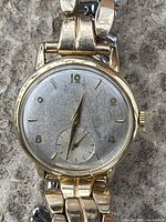 Front view showing dial, hands, sub-seconds and band attachment