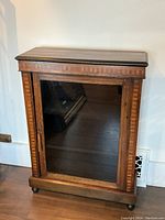 Front view of wooden cabinet showing inlaid wood details and glass door