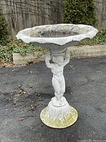 Front view of entire bird bath showing child figure pedestal and scalloped bowl