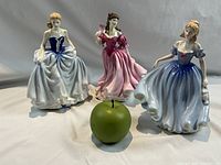 Three figurines with green apple scale reference