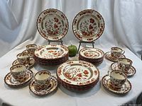 Overview of all 42 pieces: stacks of dinner plates, bread plates, soup bowls, saucers, and arranged teacups with green apple for scale