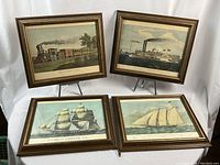 Four framed vintage transportation prints arranged on display stands, showing all items included in the lot.