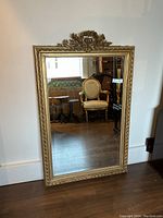 Full front view of rectangular gilt mirror leaning against wall