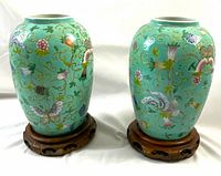 Two vases on wooden stands, front view showing overall shape and motif