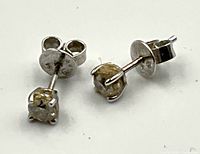 Close-up of two stud earrings on white background showing front diamond and back post