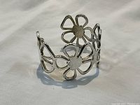 Front view of cuff bracelet showing three open flower motifs