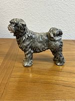 Side view showing the entire dog figurine in gray porcelain.