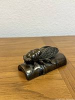 Side angle showing detailed cicada wings and bamboo stalk base.