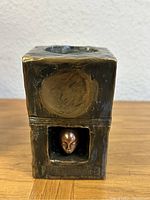 Front view of cube vase showing circular opening and lower niche with sculpted face.