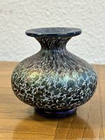 Front view of vase depicting its bulbous shape, iridescent multicolor spotted glass pattern, and wide flared rim.