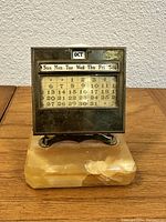 Front view of vintage perpetual glass calendar mounted on stone base showing calendar days and month OCT.