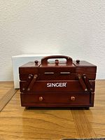 Closed vintage Singer wooden sewing box with handle and front logo