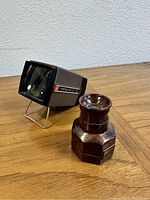 Photo showing the Pana-Vue 2 slide viewer and the wooden kaleidoscope side by side on a wood surface with a white wall background.