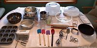 Full overview of the baking supplies lot on table including pans, mixers, spatulas, measuring cups