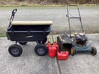 Photo showing Craftsman lawn mower, four red gas cans, and black utility rolling cart with mounted wooden seat all placed on concrete surface.
