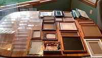 Overview of various empty frames, photo albums, and clear photo holders on a table near a window