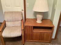 Photo showing oak cabinet with multiple compartments and a rolling upholstered chair beside it.