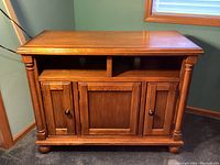 Front view of oak wood media console showing three door fronts and two open shelves above.
