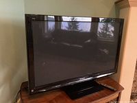 Front view of plasma TV on stand with remote beside it