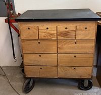Front view of the wooden rolling workshop bench with ten drawers and metal casters on the base.